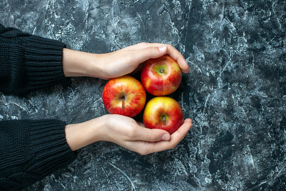 Hands holding fresh apples representing mindful eating and a balanced lifestyle.