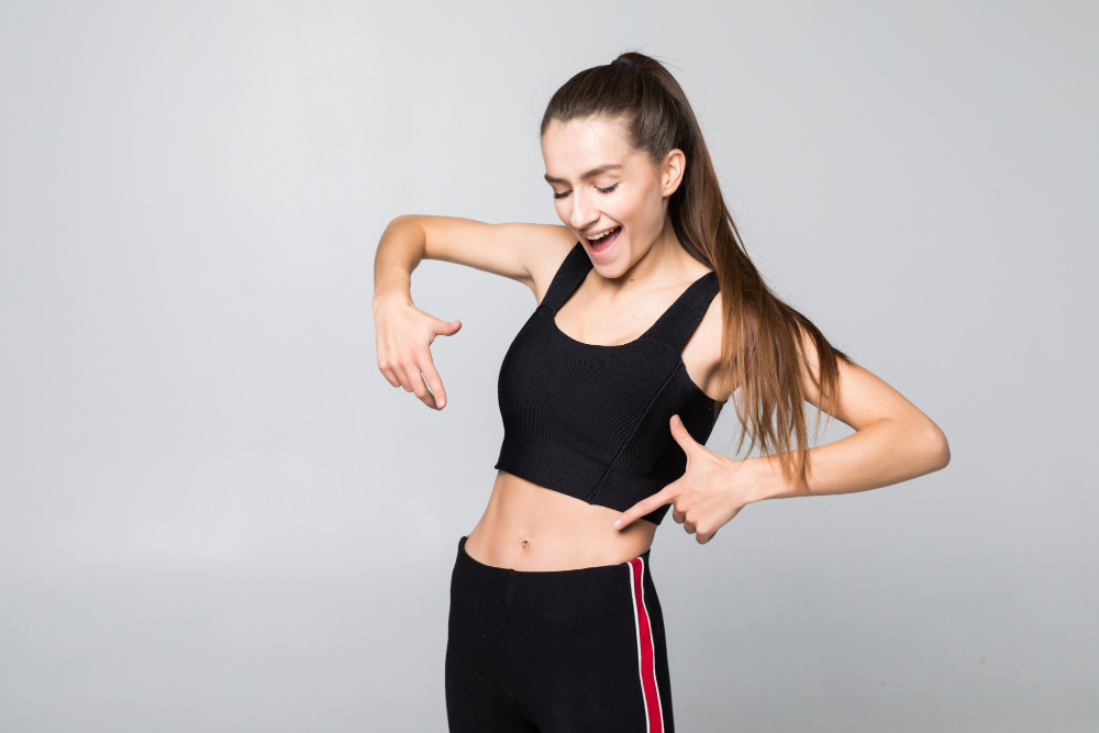Woman pointing at belly area showing focus on reducing belly fat naturally