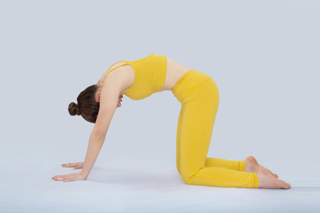 Woman practicing cat cow yoga pose to stimulate digestion and reduce bloating