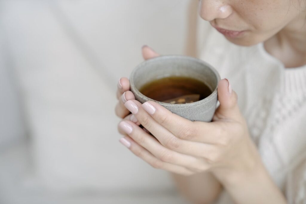 person holding warm black pepper water in cup for daily wellness and digestion support