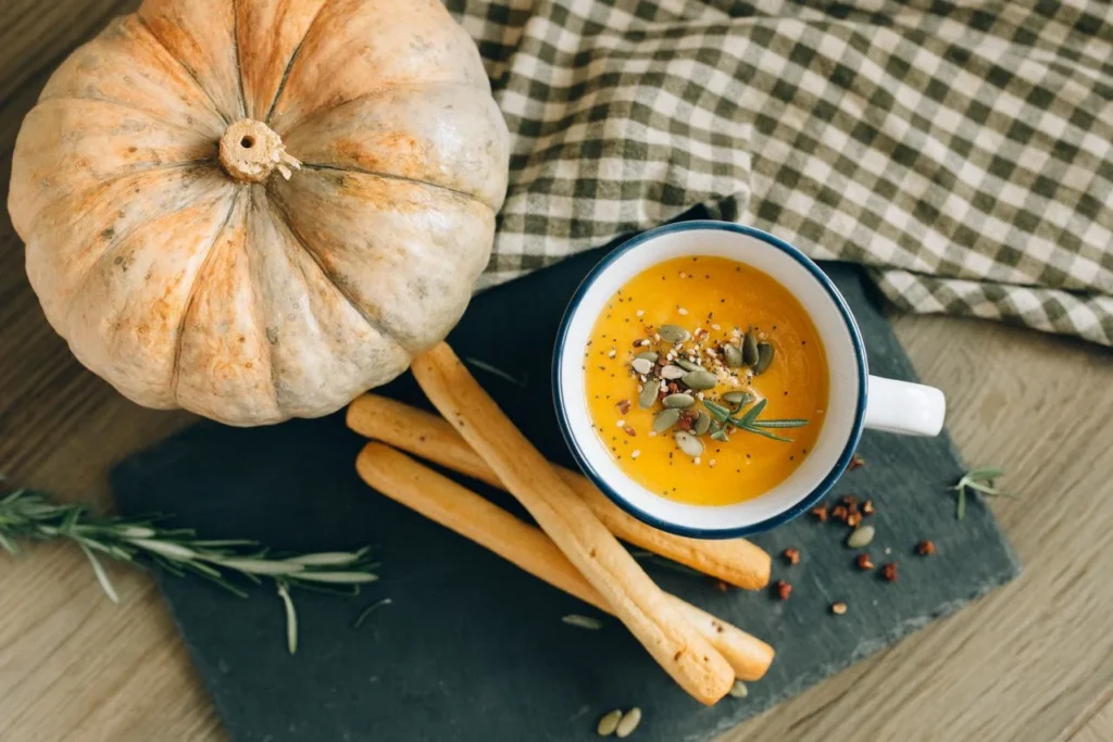 Bowl of creamy pumpkin soup topped with pumpkin seeds, showing a simple and healthy way to include pumpkin seeds in your daily diet.